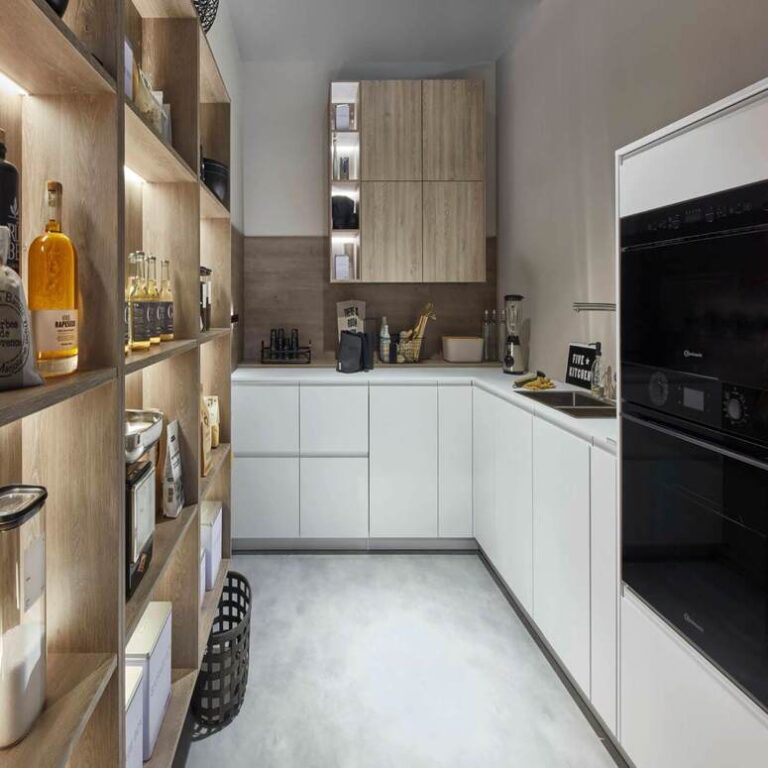 Moderne weiße Küche mit Hochschränken, Holzregal und schwarzen Einbaugeräten – Küche kaufen Gütersloh